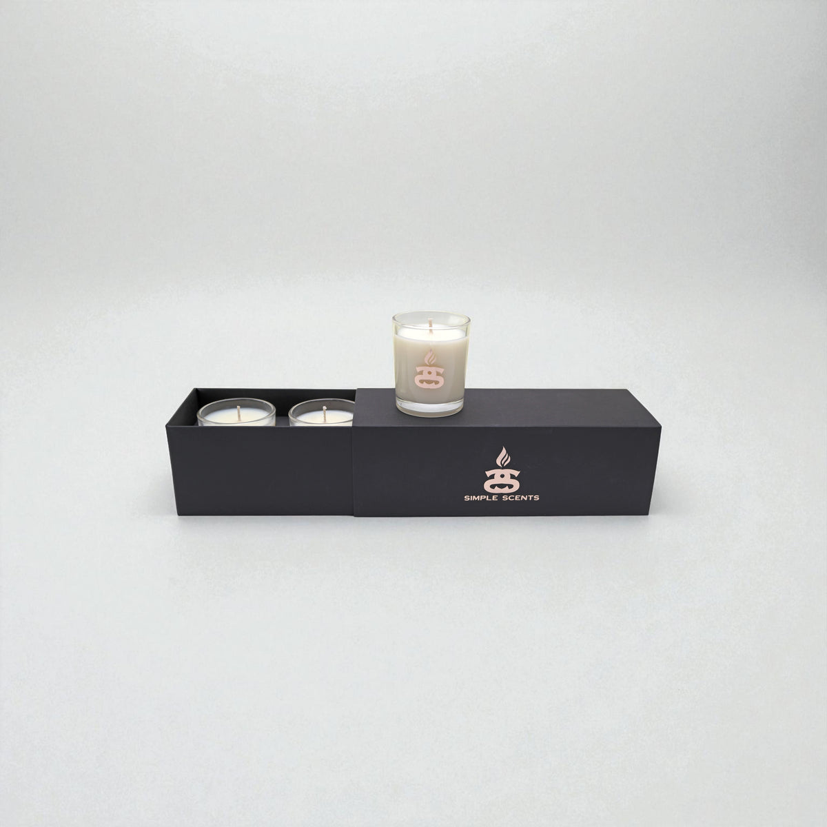 Simple Scents Mini Indulgence Trio Luxury Soy Candles 75g - three votive candles in glass jar with rose gold Simple Scents logo, displayed in open matte black rectangular gift box on white background