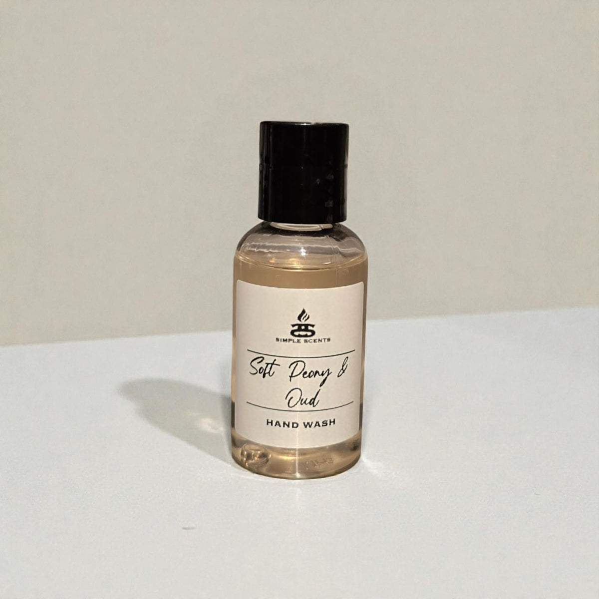 Simple Scents Minis Soft Peony & Oud Hand Wash 50ml - small clear glass bottle with black cap and Simple Scents label, front view on white surface with light grey background