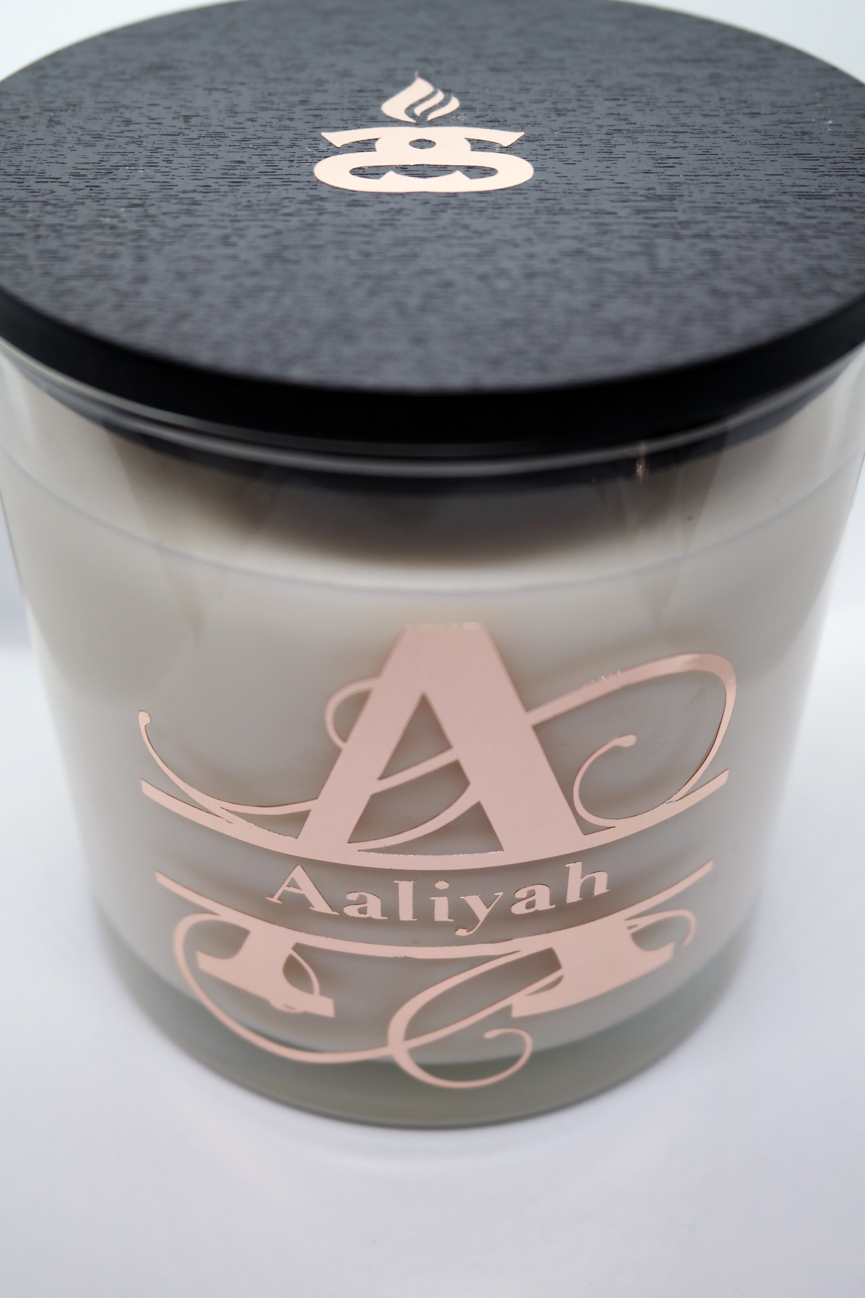 Large candle glass with a black wooden lid, The name Aaliyah written on the front of the candle jar.