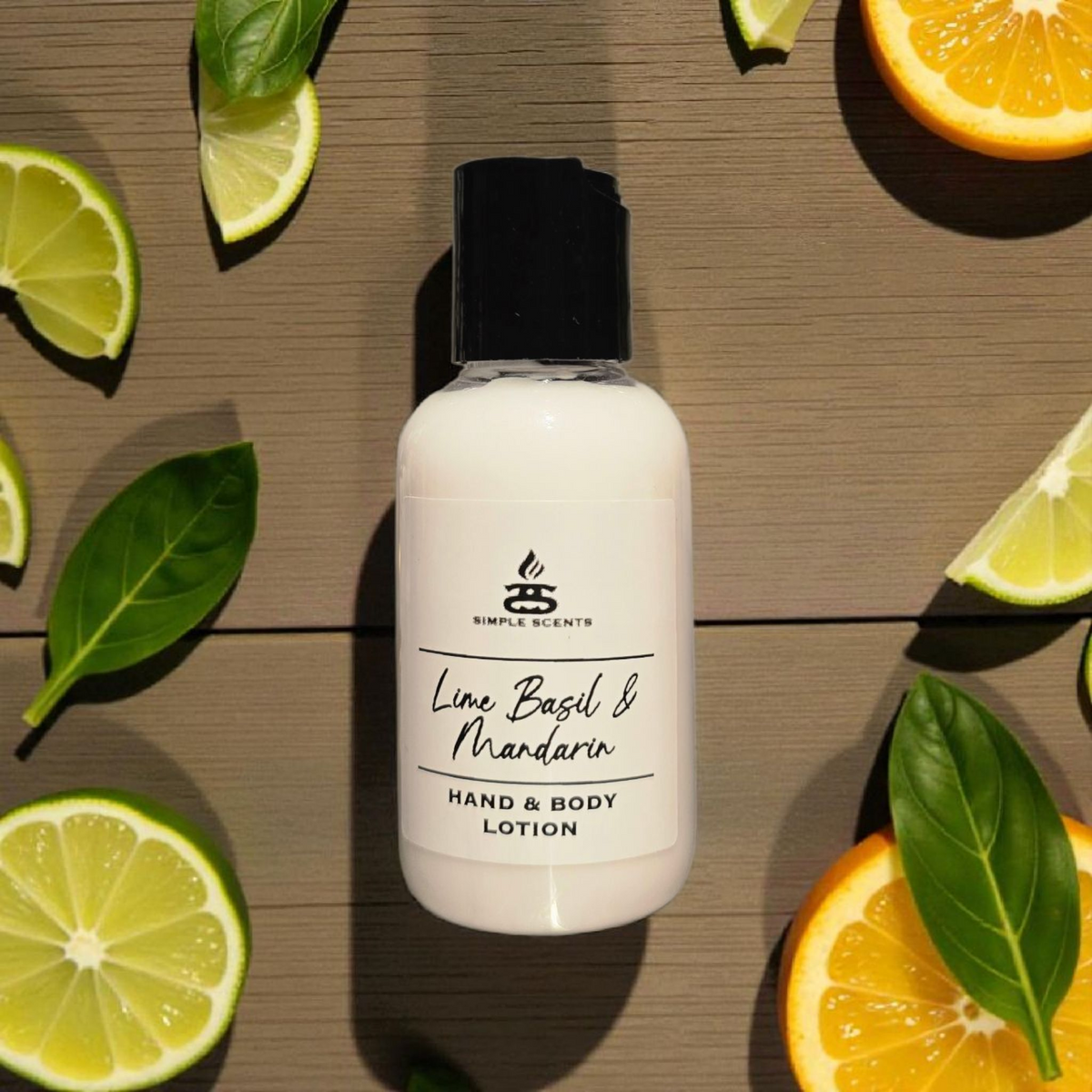 Simple Scents Minis Lime Basil & Mandarin Hand & Body Lotion 50ml - small white pump bottle with black flip cap and Simple Scents label, flat lay overhead view on wooden slat surface surrounded by lime wedges, orange halves and green basil leaves