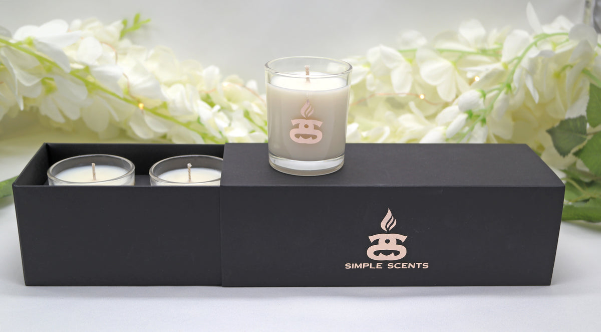 Simple Scents Mini Indulgence Trio Luxury Soy Candles 75g - two mini tea light candles and one votive candle on open black gift box with white floral backdrop