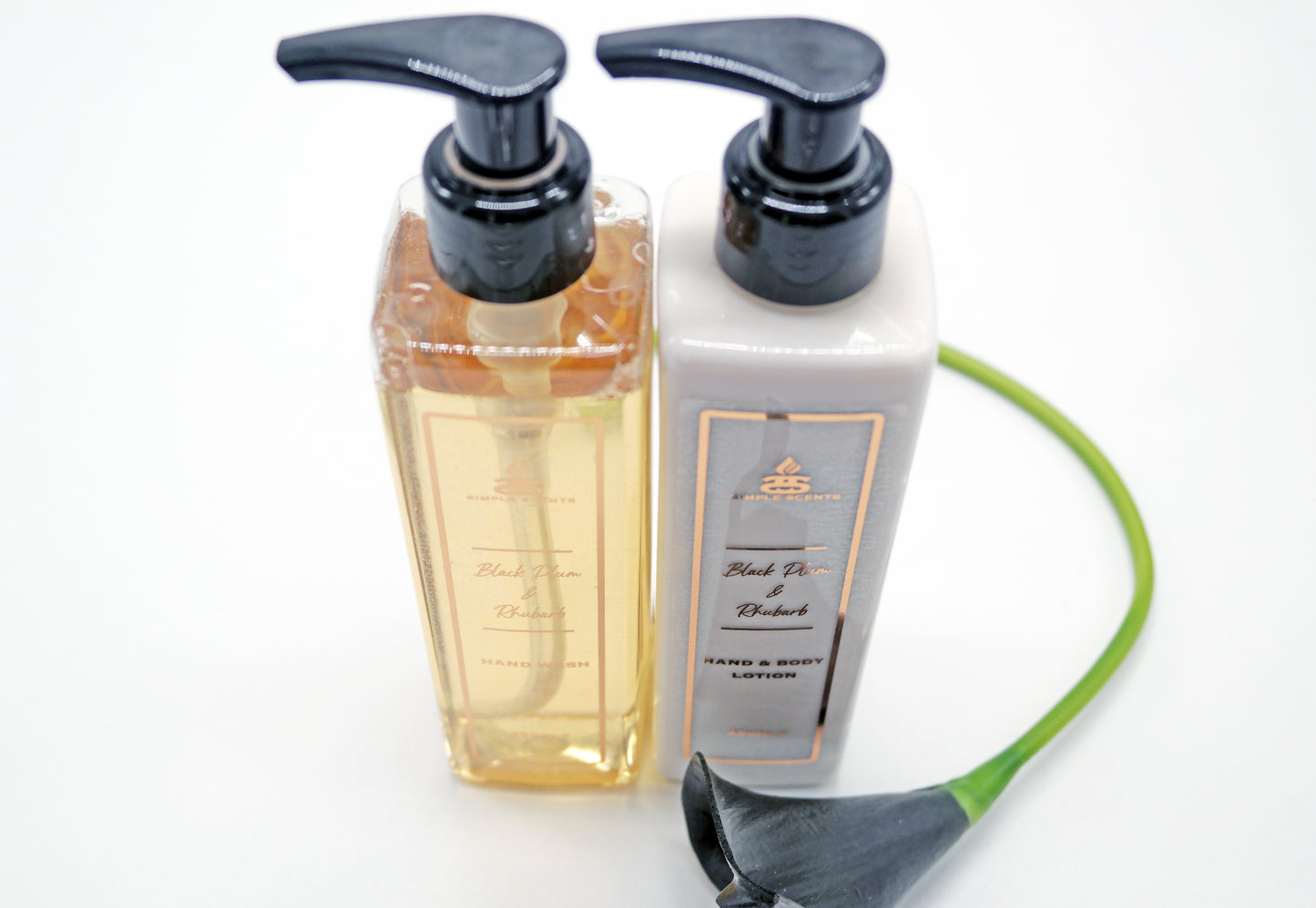 Black Plum & Rhubarb Hand Wash and Lotion in bottles next to black lily