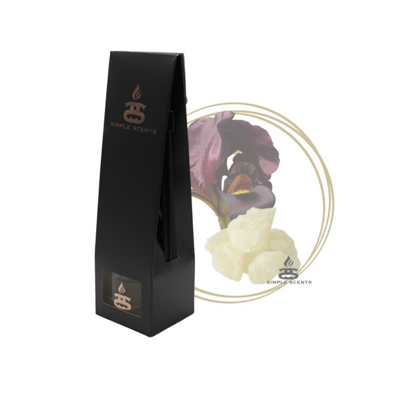 Black Iris and Musk Simple Scents Excellence Reed Diffuser - matte black tall tapered packaging box with rose gold Simple Scents logo, displayed in front of a dark purple iris flower and white musk crystals on white background