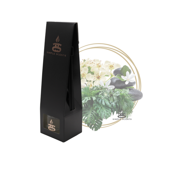 Tropical Garden Simple Scents Excellence Reed Diffuser - matte black tall tapered packaging box with rose gold Simple Scents logo, displayed in front of white orchids, tropical leaves and dark spa stones inside a gold double-ring circle frame on white background