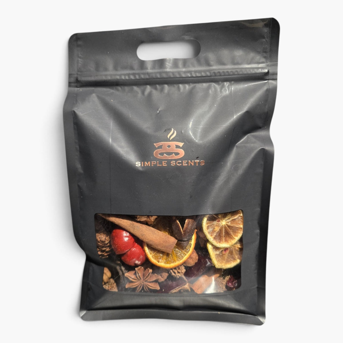 A black resealable stand-up pouch with a die-cut handle and a clear window showing dried orange slices, cinnamon sticks, star anise, and red berries inside. The pouch has a Simple Scents logo printed in gold near the top.