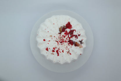 Simple Scents Aromatherapy Eucalyptus & Peppermint Bath Bomb with dried botanicals and red pomegranate flower petals on top, viewed from above on a light grey background