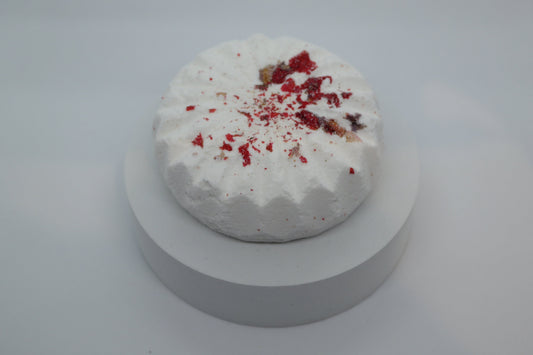 Simple Scents Aromatherapy Eucalyptus & Peppermint Bath Bomb with red pomegranate flower petal botanical topping, displayed on a white round plinth