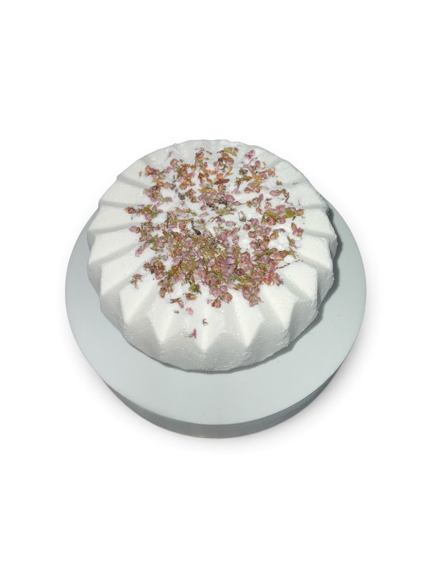 Simple Scents Tea Tree and Rosemary Aromatherapy Bath Bomb with dried heather floral botanicals on top, displayed on a white pedestal against a white background