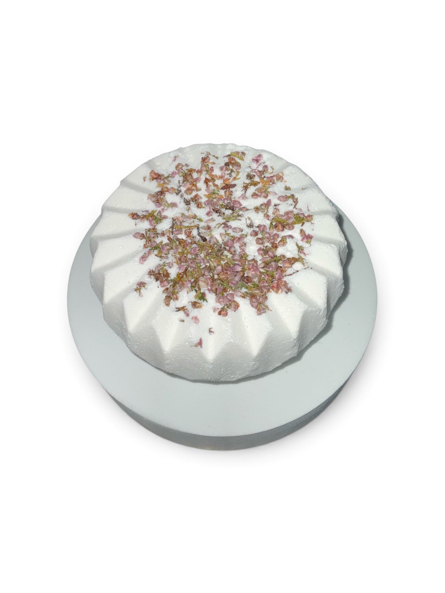 Simple Scents Tea Tree and Rosemary Aromatherapy Bath Bomb with dried heather floral botanicals on top, displayed on a white pedestal against a white background