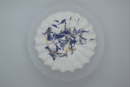Simple Scents Aromatherapy Lavender & Frankincense Bath Bomb topped with dried blue cornflower petals, viewed from above on a light grey background