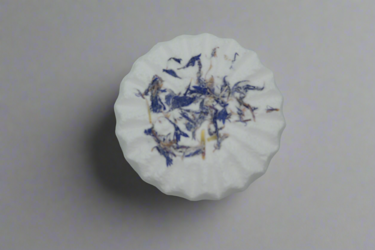 Close-up top view of Simple Scents Aromatherapy Lavender & Frankincense Bath Bomb with dried blue cornflower petals scattered across the surface