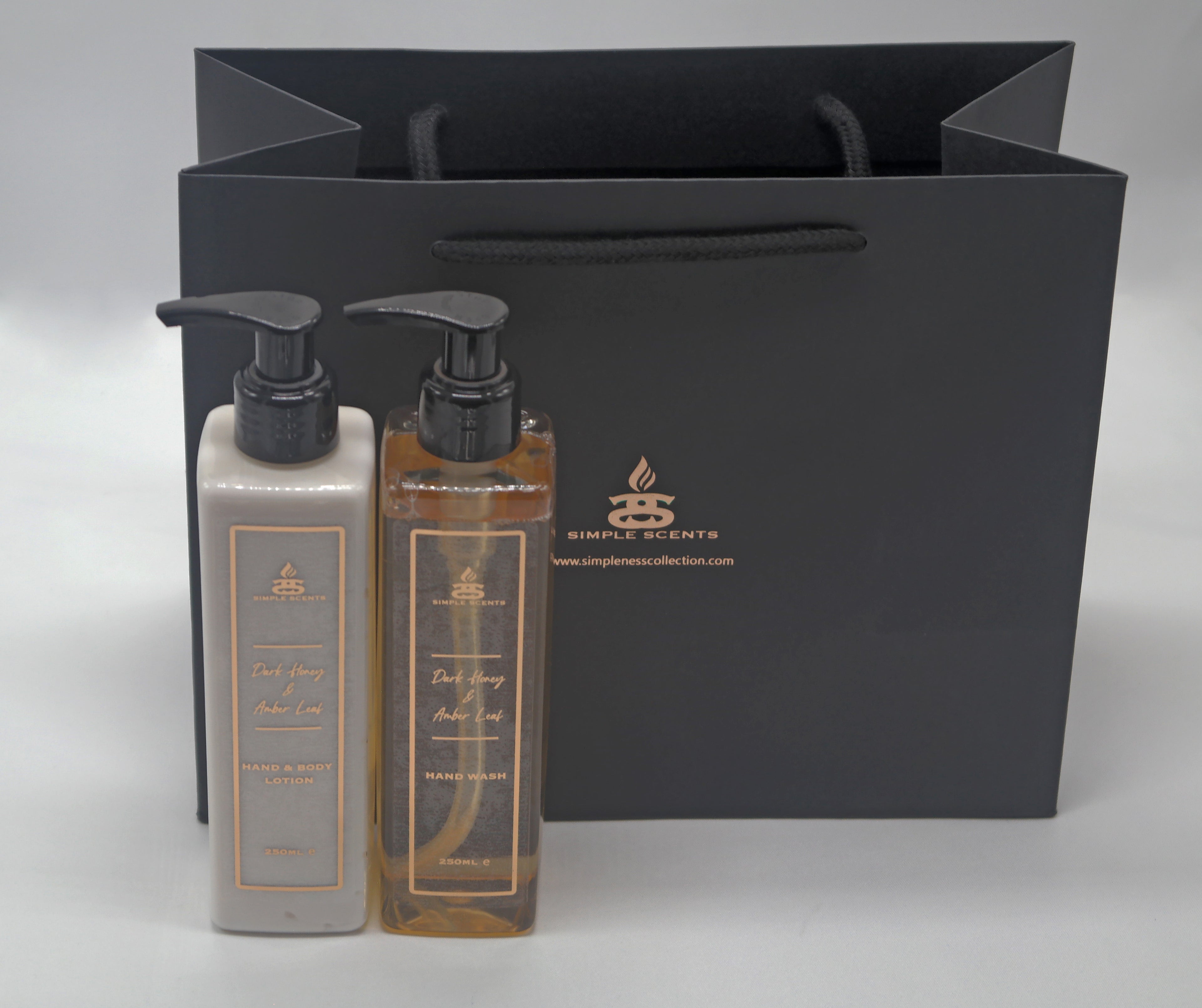 Simple Scents Dark Honey & Amber Leaf Hand Wash and Lotion in front of black gift bag