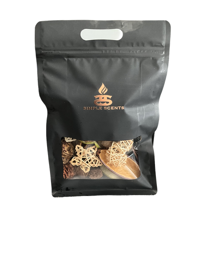A black resealable stand-up pouch with a die-cut handle and a clear window near the bottom, showing dried botanicals and decorative wicker pieces inside. The pouch has a metallic rose-gold logo reading 'Simple Scents' on the front, set against a plain white background.