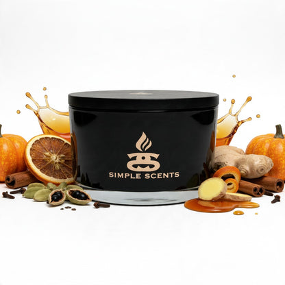 umpkin Vale candle with its black lid on, styled with pumpkins, orange, ginger, cinnamon and cardamom against a white background.